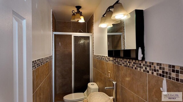 bathroom with toilet, a stall shower, and tile walls