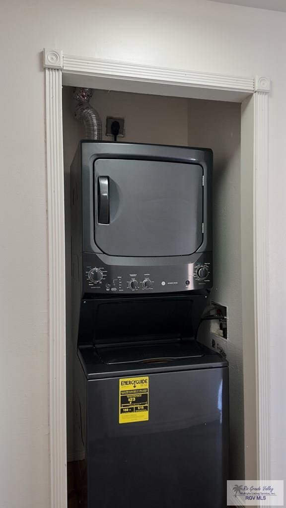 clothes washing area featuring stacked washing maching and dryer and laundry area