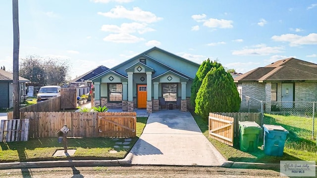 view of front of house featuring stone siding, a fenced front yard, stucco siding, and a gate