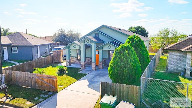 bungalow-style house with concrete driveway, stone siding, a gate, a front yard, and fence private yard