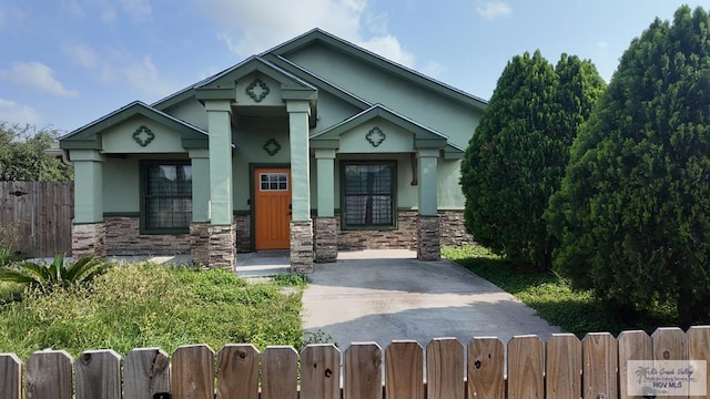 view of front facade featuring stucco siding, a gate, stone siding, and a fenced front yard