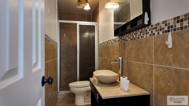 bathroom featuring toilet, a stall shower, and tile walls