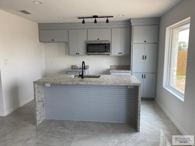 kitchen featuring gray cabinetry, light stone counters, sink, and a healthy amount of sunlight