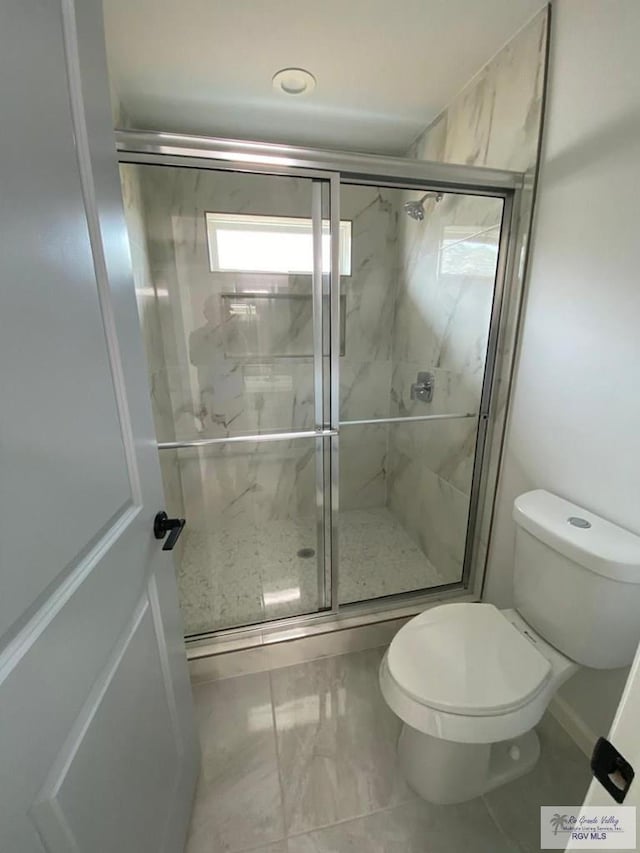 bathroom featuring toilet and a shower with door