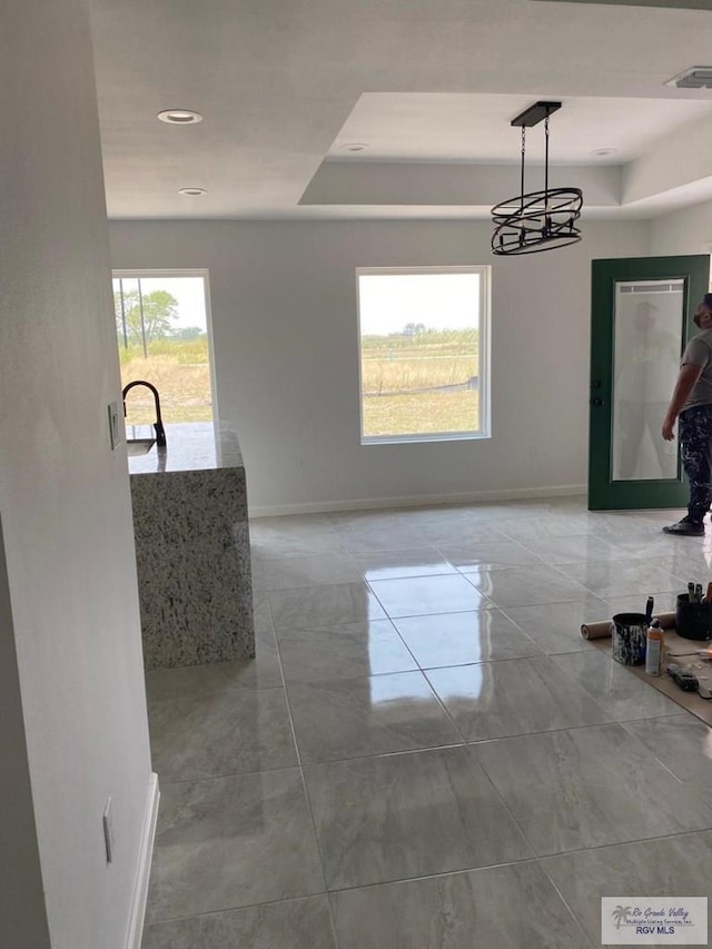 unfurnished dining area featuring a tray ceiling and an inviting chandelier