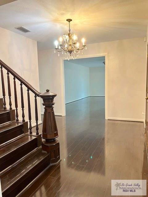 staircase with hardwood / wood-style floors and a chandelier