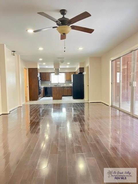 unfurnished living room with ceiling fan, dark hardwood / wood-style flooring, and sink