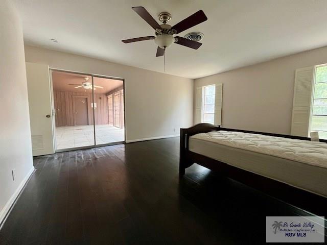 bedroom with ceiling fan, dark wood-type flooring, and a closet