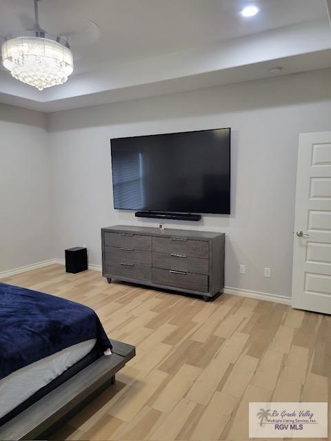 bedroom with light hardwood / wood-style flooring and a notable chandelier