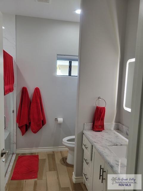 bathroom featuring vanity, a shower with shower door, and toilet