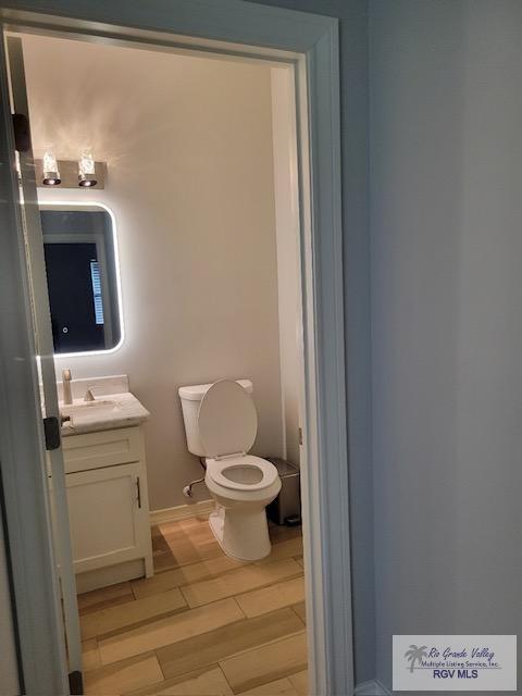 bathroom featuring toilet, vanity, and hardwood / wood-style flooring