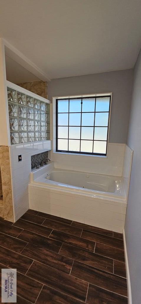 bathroom featuring a wealth of natural light and tiled bath