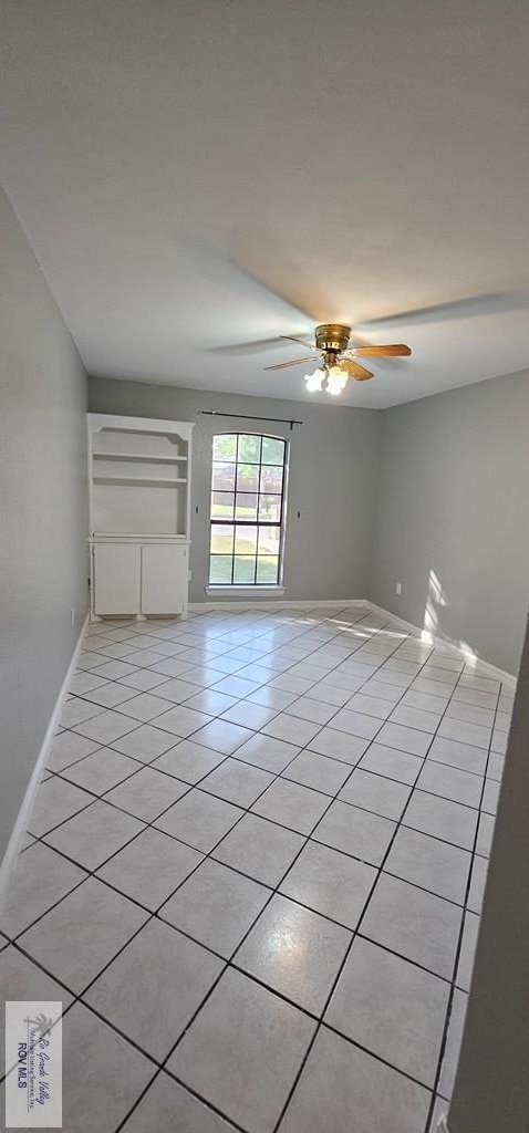 tiled empty room featuring ceiling fan