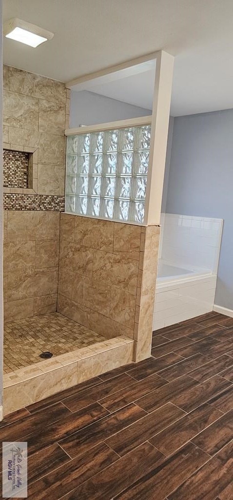 bathroom featuring hardwood / wood-style floors and a relaxing tiled tub