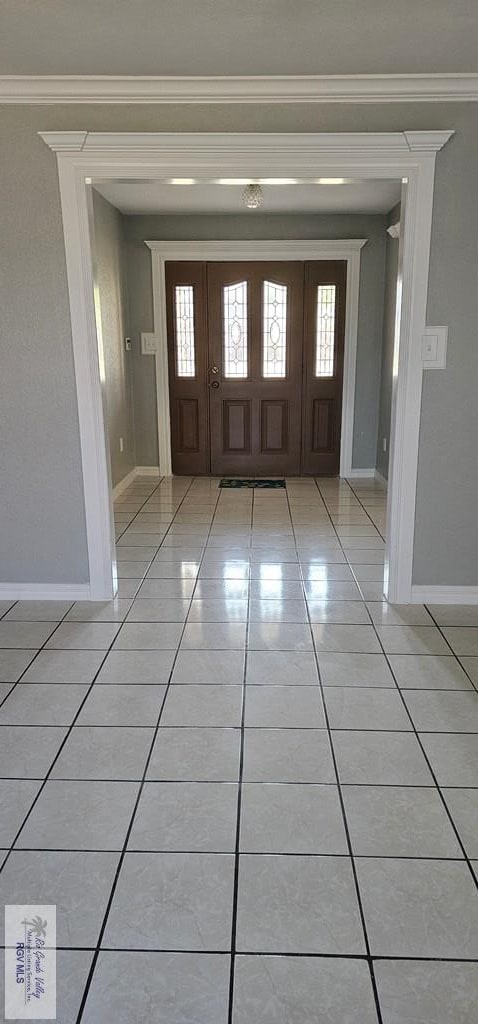 foyer featuring light tile patterned flooring and crown molding