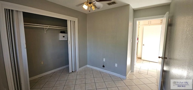 unfurnished bedroom featuring ceiling fan, light tile patterned floors, and a closet