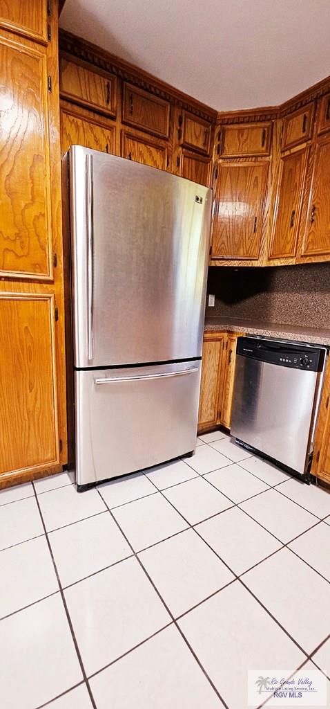 kitchen featuring backsplash, light tile patterned flooring, and stainless steel appliances