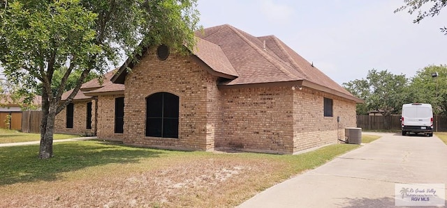 view of property exterior with central AC unit and a yard