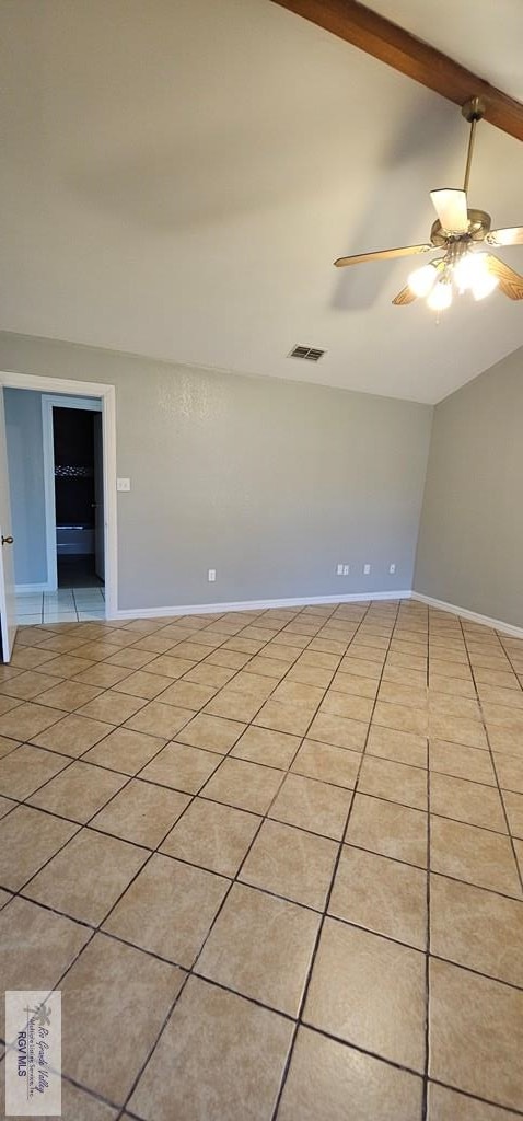 tiled spare room featuring ceiling fan and lofted ceiling with beams