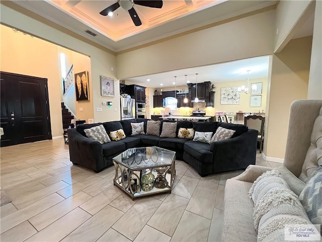 living room featuring a high ceiling, ceiling fan with notable chandelier, and ornamental molding