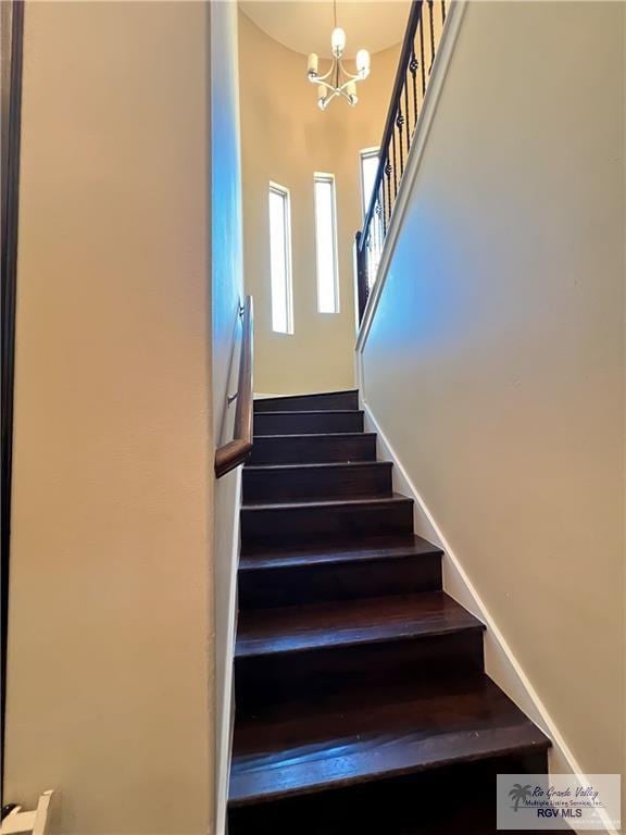 staircase with a notable chandelier