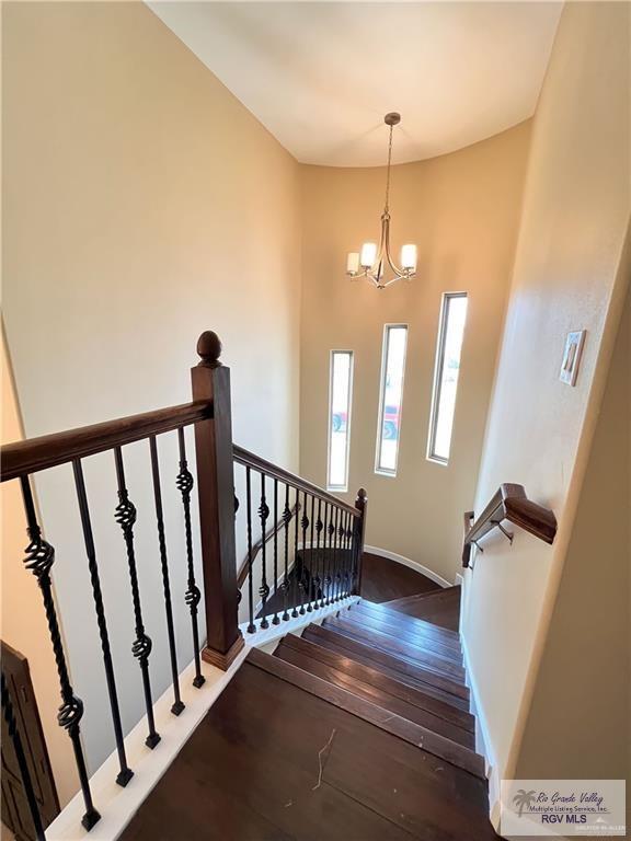 stairs featuring hardwood / wood-style floors and an inviting chandelier