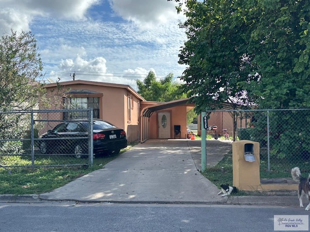 view of front of house with concrete driveway, fence, and stucco siding