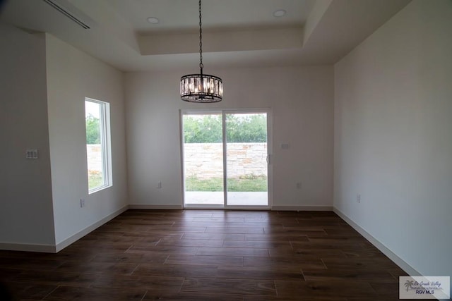 1272 Bridle Way, San Benito, TX 78586 - empty room featuring a raised ceiling, a chandelier, and dark wood-style flooring