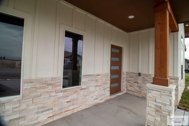 1272 Bridle Way, San Benito, TX 78586 - doorway to property with board and batten siding, stone siding, and a porch