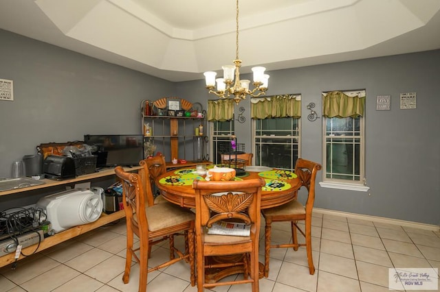 tiled dining area featuring a tray ceiling and a notable chandelier