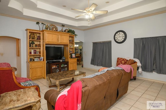 tiled living room with ceiling fan with notable chandelier, a raised ceiling, and crown molding