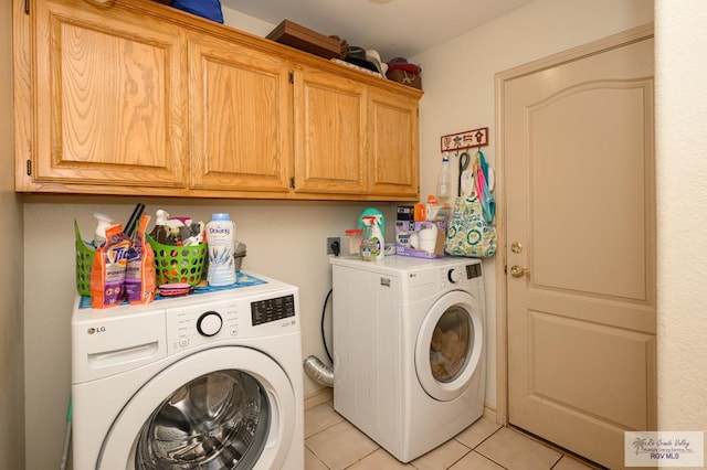 clothes washing area with washer and clothes dryer, light tile patterned floors, and cabinets