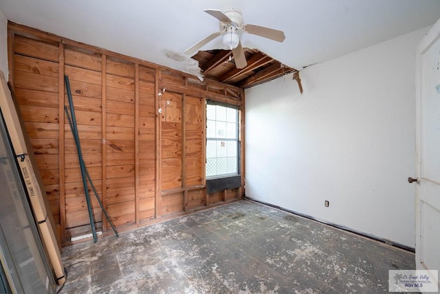 empty room with ceiling fan and wooden walls