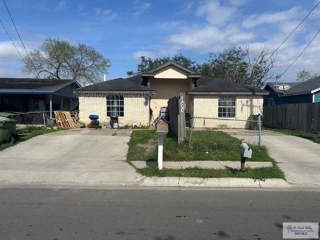 view of front of property with a fenced front yard, concrete driveway, and brick siding