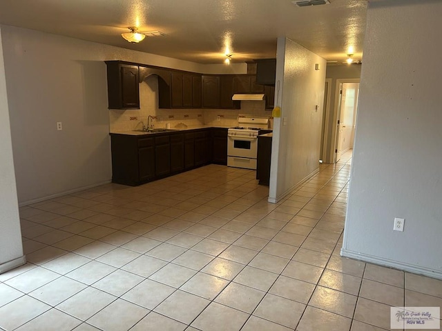 kitchen with white range with gas cooktop, light countertops, dark brown cabinets, under cabinet range hood, and a sink