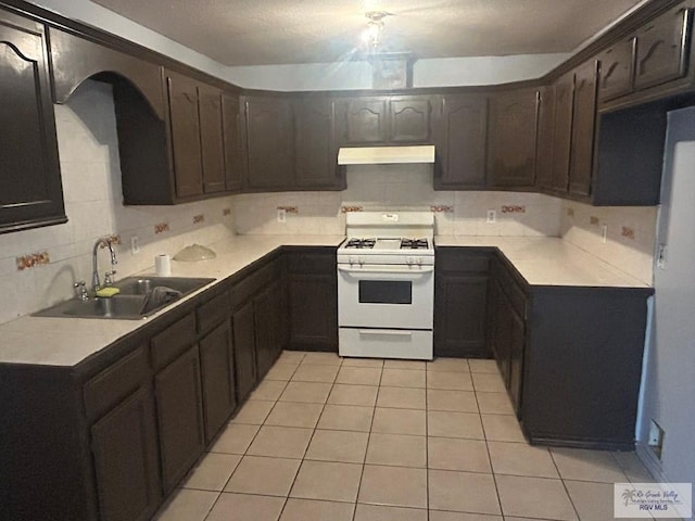 kitchen featuring under cabinet range hood, white range with gas cooktop, light countertops, and a sink