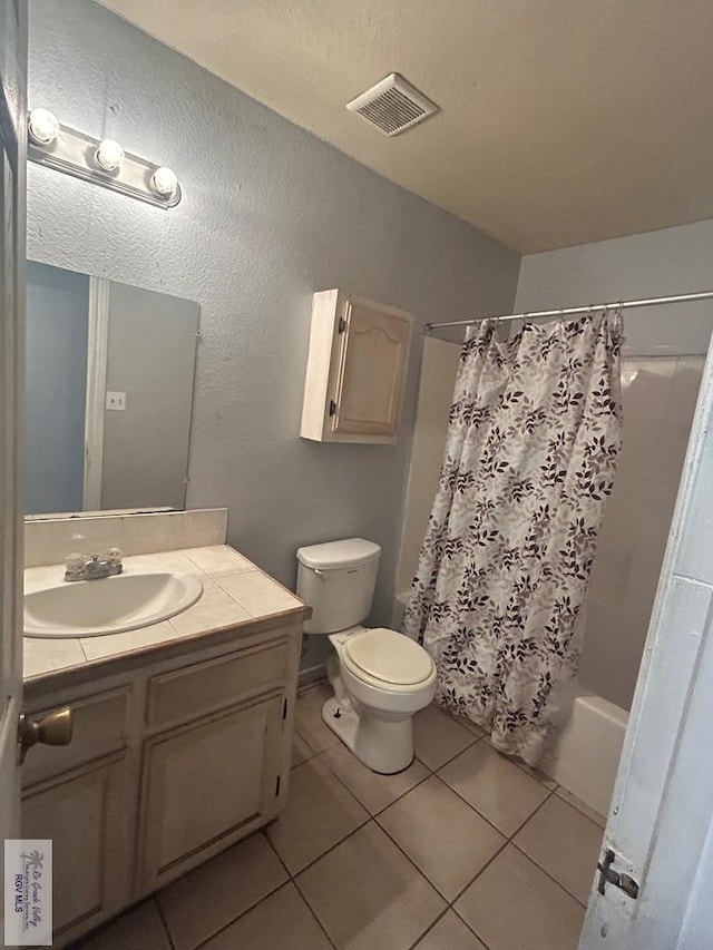 bathroom featuring toilet, vanity, visible vents, tile patterned floors, and shower / bath combination with curtain