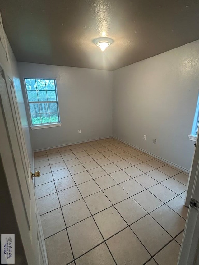 empty room featuring a textured ceiling and light tile patterned floors