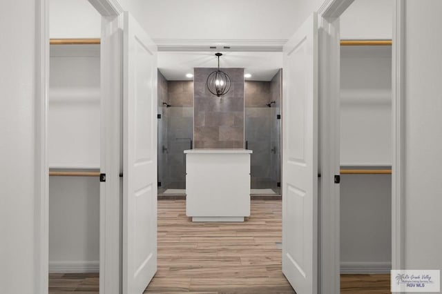 bathroom with tiled shower, hardwood / wood-style floors, and a notable chandelier