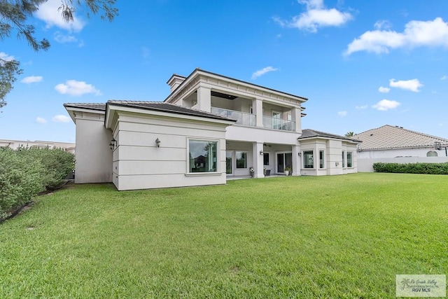 back of house featuring a yard and a balcony