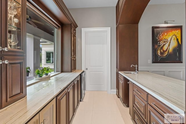 bar with light stone countertops, sink, and light tile patterned floors