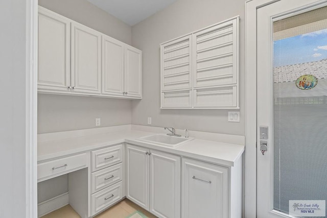 kitchen featuring light tile patterned flooring, white cabinetry, and sink