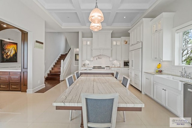 tiled dining area with beamed ceiling, coffered ceiling, and sink