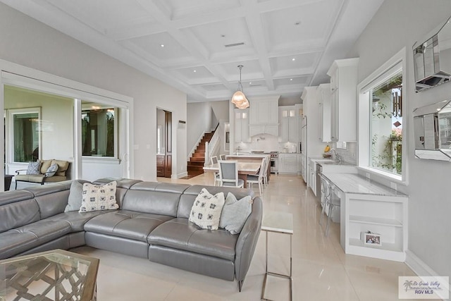 living room with light tile patterned floors, beamed ceiling, coffered ceiling, and sink