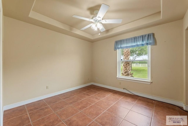 12612 E Clark Rd, La Feria, TX 78559 - spare room with a tray ceiling, light tile patterned floors, and baseboards