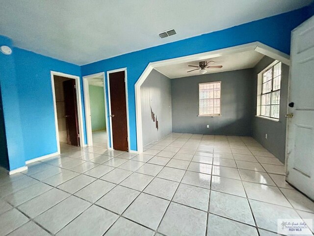 tiled empty room featuring ceiling fan