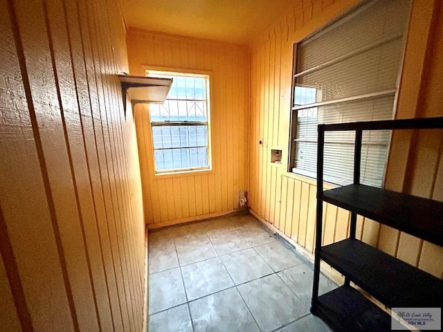 empty room with light tile patterned floors and wood walls