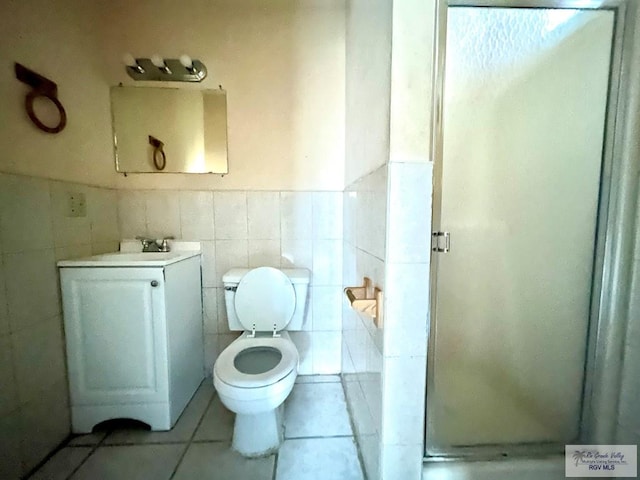 bathroom with tile patterned flooring, vanity, a shower with door, and tile walls