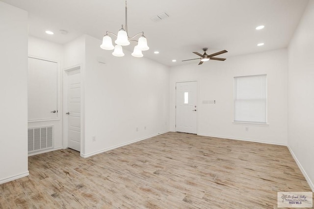 unfurnished room featuring ceiling fan with notable chandelier and light wood-type flooring