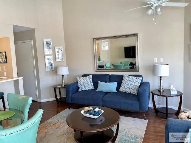 living room featuring dark hardwood / wood-style floors, ceiling fan, and a high ceiling